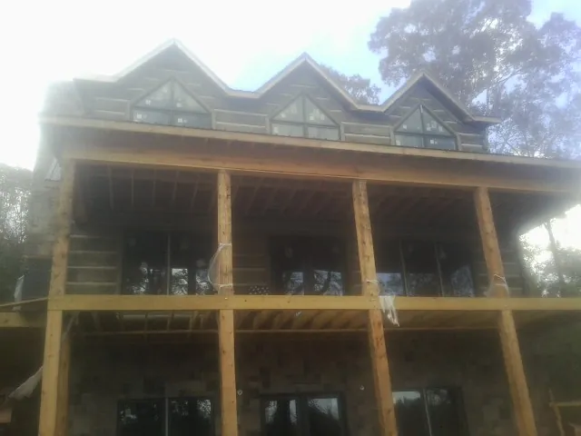 Dormers and porch framing on a large log home under construction — Roof Coating work by our crew in North Brunswick
