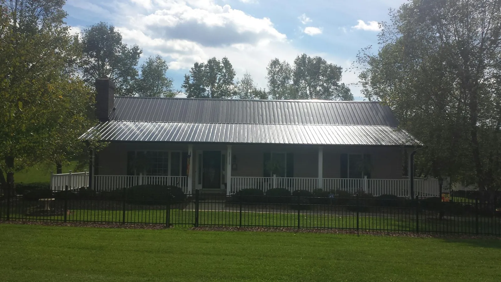 Gray metal roof on a brick ranch with a full width front porch — Gutter Guard Installation work by our crew in North Brunswick