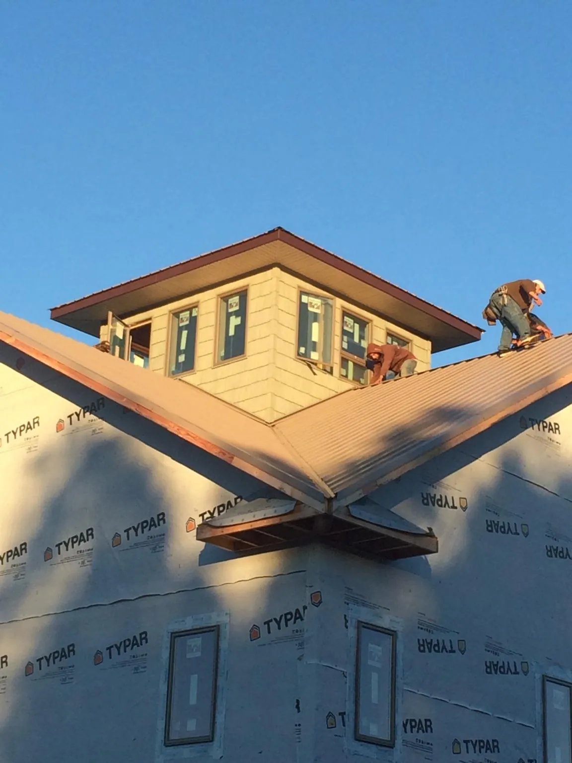 Roofers working around a rooftop cupola on a new metal roof at sunset — Roof Waterproofing in North Brunswick by Roofing Brothers